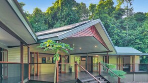 A two-story house with a covered porch, a staircase, and a view of a forested area. - The Canopy- Stunning elevated home (Bingil Bay)