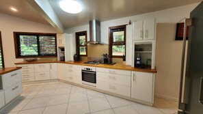 A kitchen with white cabinets, a gas stove, a built-in oven, and a stainless steel range hood.