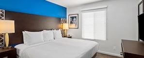 A hotel room with a large bed, two bedside lamps, a framed picture on the wall, a window with blinds, and a TV on a stand. - F1 LAS VEGAS 2026 - 2BR RESORT FOR 6 - NOV 19-22 - 392/NIGHT (Las Vegas)