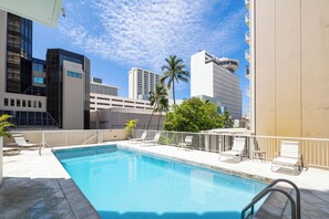 A swimming pool with lounge chairs and a view of tall buildings. - Free Parking Newly Renovated New Kitchen 4th FL (Honolulu)