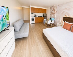 A hotel room with a sofa, a bed, a kitchenette, and a television. - Free Parking Newly Renovated New Kitchen 4th FL (Honolulu)