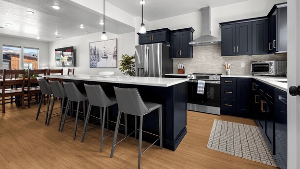 A modern kitchen with a large island, bar stools, stainless steel appliances, and dark cabinetry. - Powderline Lodge | Hot Tub | 2 King Suites | Ski (Mountain Green)