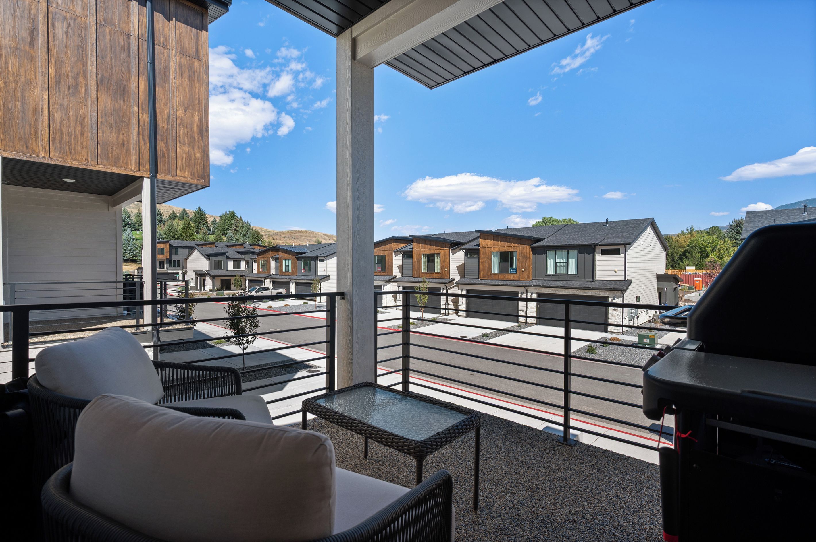 Un balcon aménagé avec du mobilier d’extérieur, un barbecue et une vue sur les maisons voisines.