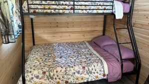 En våningssäng med ett blommigt överkast och två kuddar, placerad framför en vägg av trä.