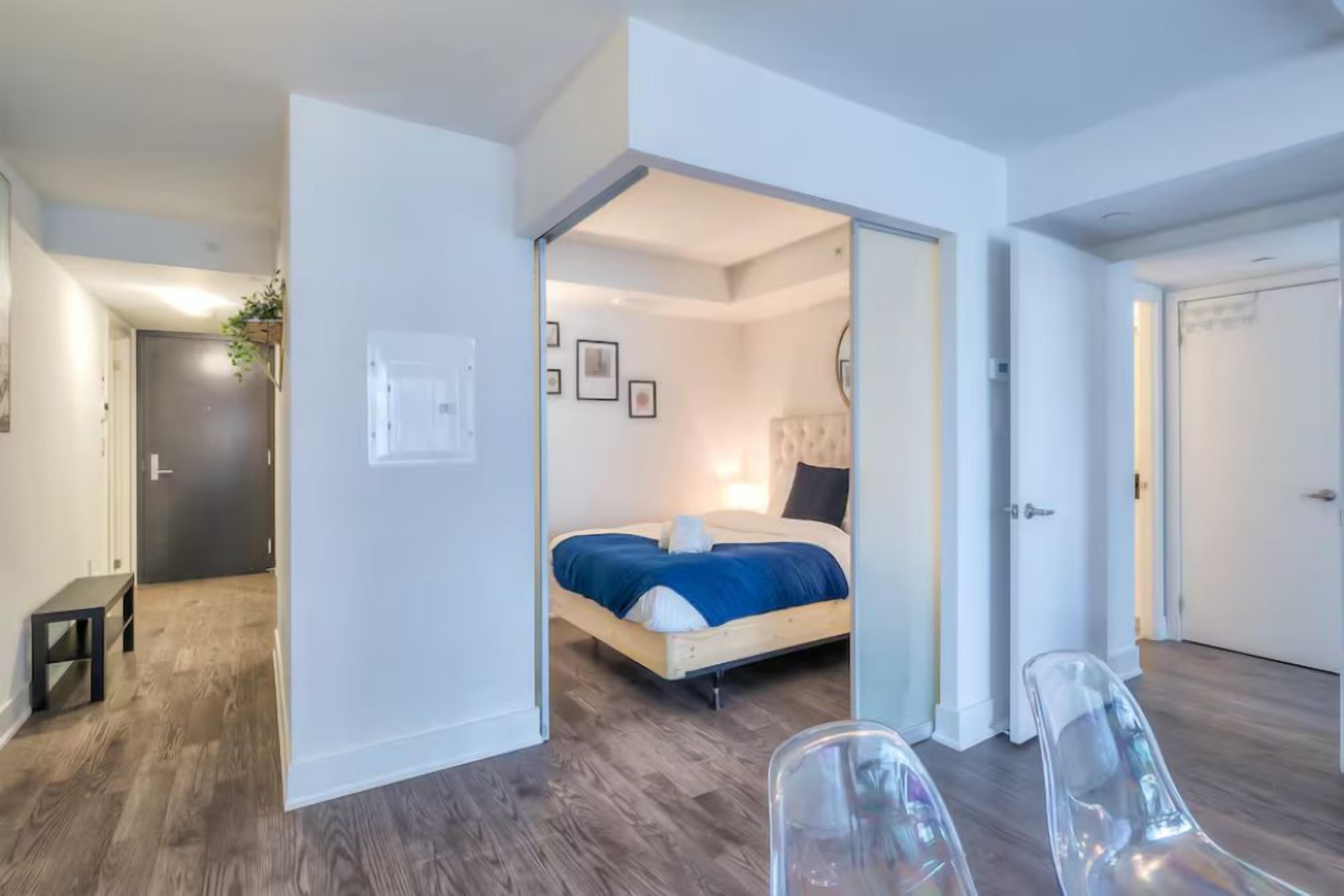 A room with a bed, a bench, and a clear chair.