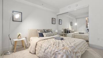 A bedroom with a large bed, bedside tables, a mirror, and a floor lamp.