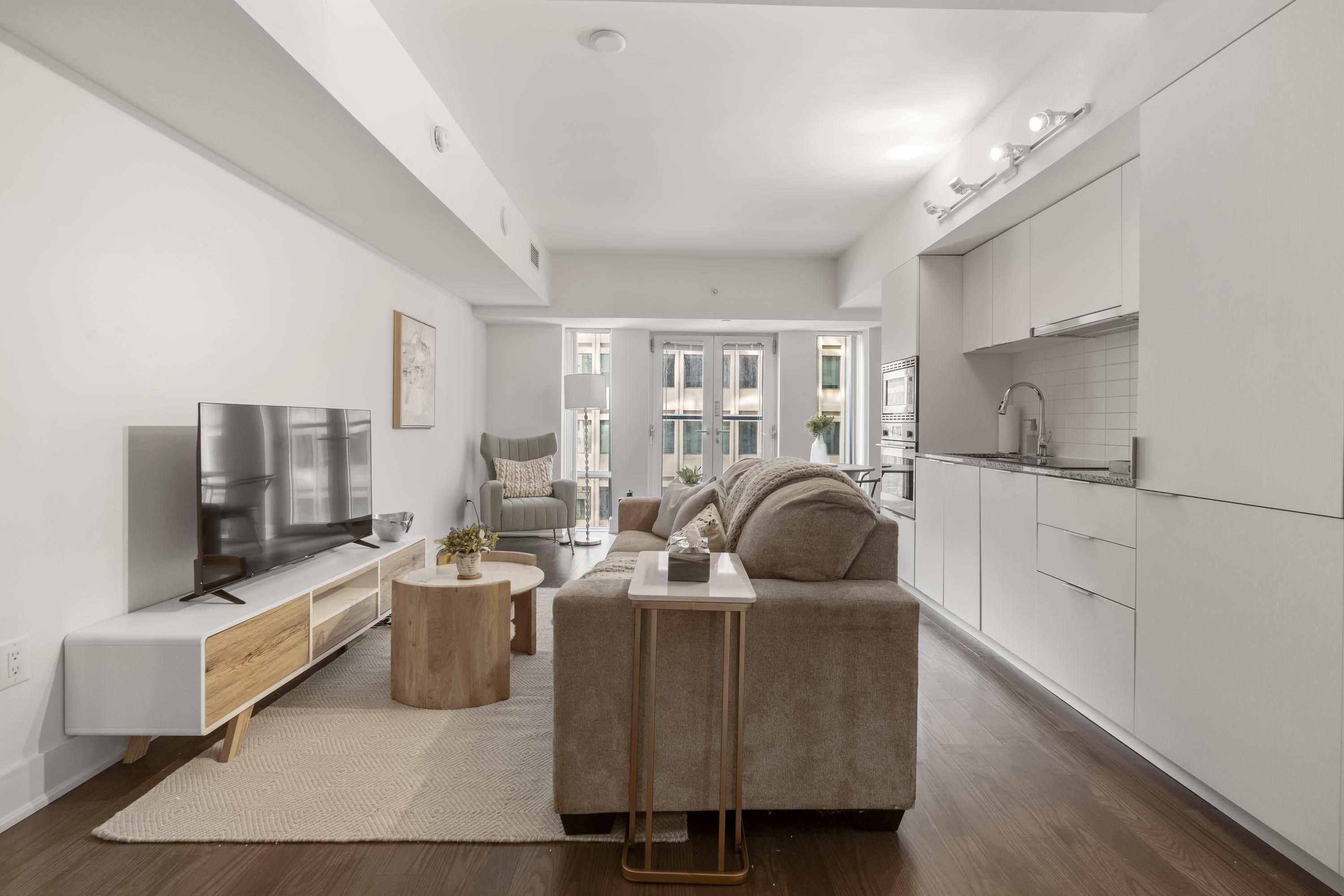 A modern living room with a flat-screen TV, a sofa, a coffee table, and a small side table.