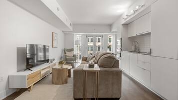 A modern living room with a flat-screen TV, a sofa, a coffee table, and a small side table.