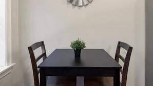 Une table à manger avec deux chaises, une plante en pot et un miroir décoratif accroché au mur.
