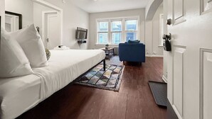 Une chambre d’hôtel équipée d’un lit, d’un bureau, d’une chaise, d’une télévision et d’une fenêtre avec des stores.