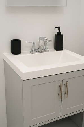 A bathroom with a white sink, a black soap dispenser, and a black container. - Boystown Chic 2BR Escape (Chicago)