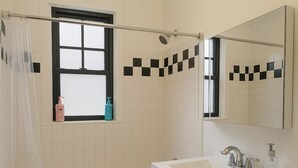 A bathroom with a bathtub, a sink, a mirror, and a window with a curtain. - 1BR Fully Equipped & Central (Chicago)