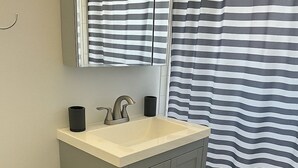 Et badeværelse med toilet, vask og spejl.