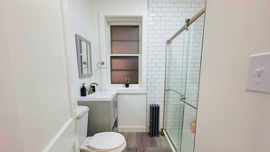 A compact bathroom with a toilet, sink, and window. - Chic & Fully Furnished 2BR Apartment (Chicago)