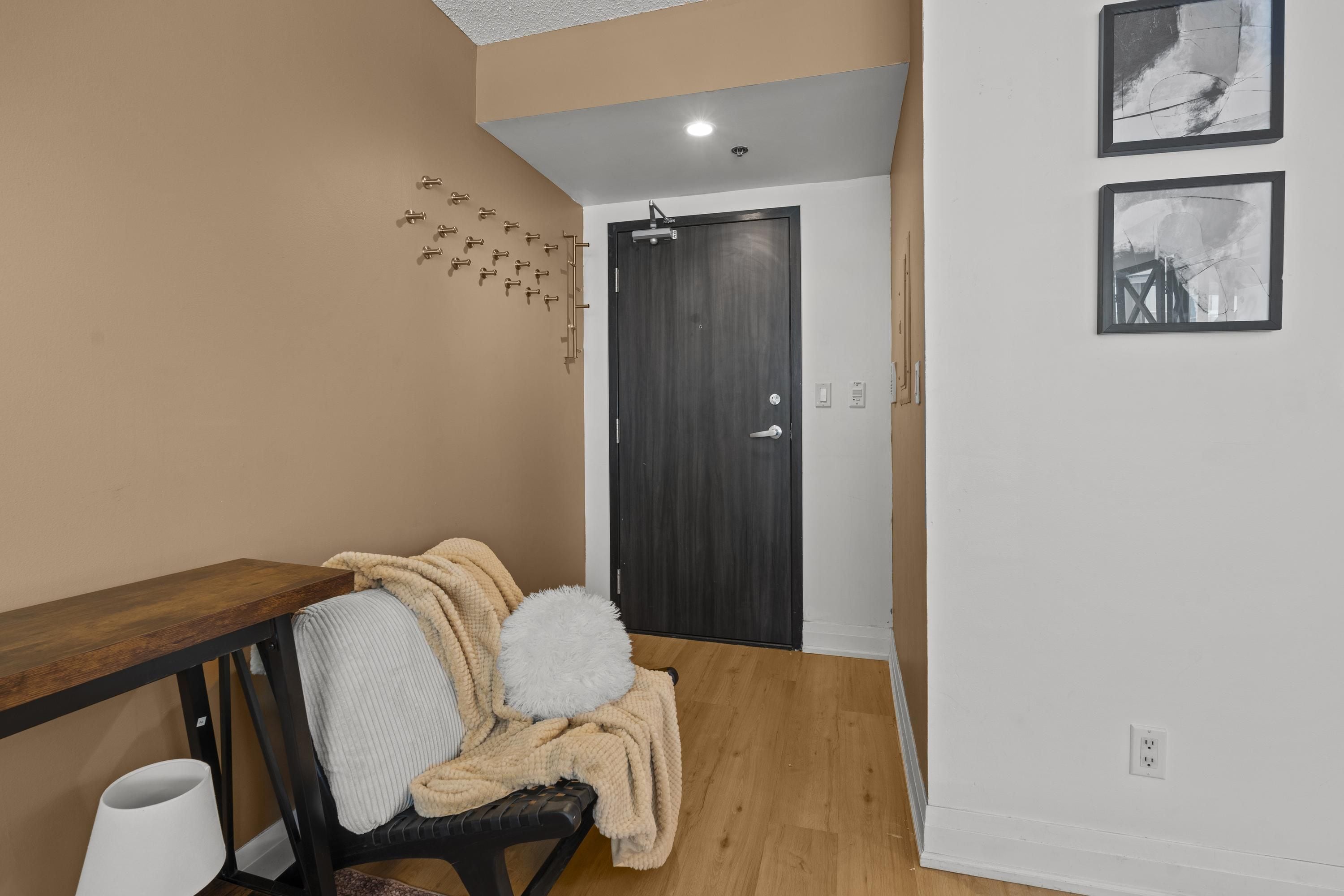 Un pasillo con un banco de madera, una puerta y dos cuadros en la pared.