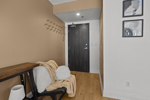 A hallway with a wooden bench, a door, and two framed pictures on the wall. - The Victoria Stay (Toronto)