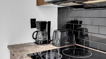 A kitchen with a black coffee maker, toaster, and black-tiled backsplash.