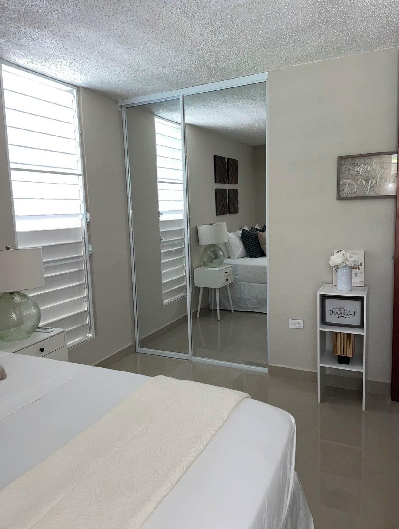 Un dormitorio con una cama, una mesita de noche, un espejo y un armario.