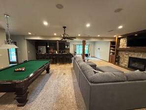A pool table with balls, a bar area, a sofa, and a fireplace. - 5-bedroom house in New London Waterfront, Pickleball,Basketball,Fishing,Gameroom (New London)