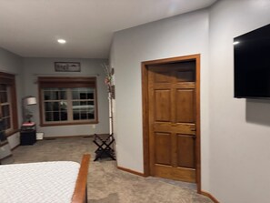 A hallway with a wooden door, a wall-mounted TV, and a window with blinds.