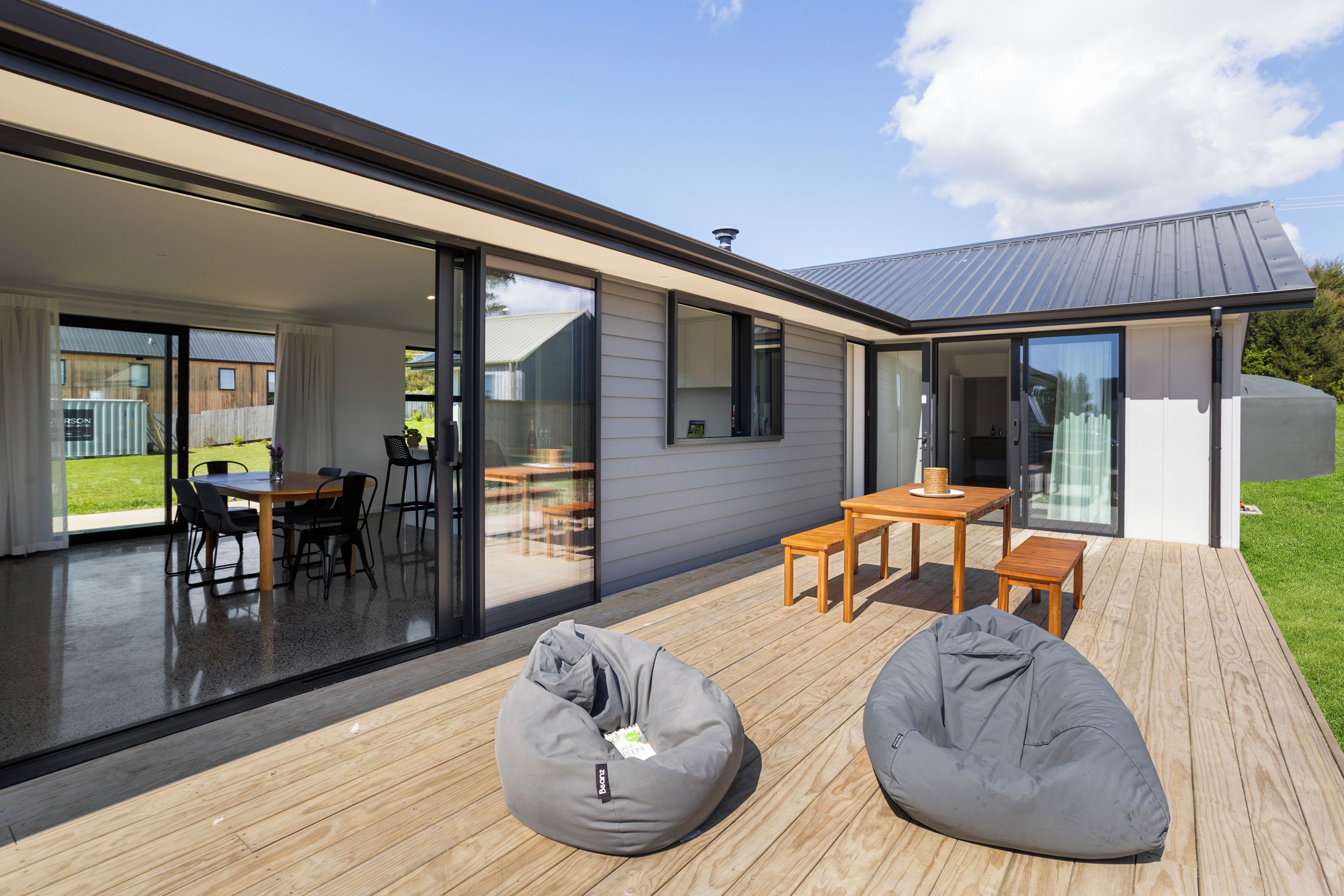 Et moderne hus med terrasse, skydedøre og spiseområde.