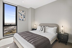 Una camera da letto moderna con un letto grande, due comodini, una lampada da terra e vista sulla città attraverso una grande finestra.