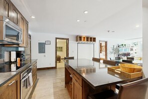 Cozinha moderna com ilha central, armários de madeira e micro-ondas embutido.