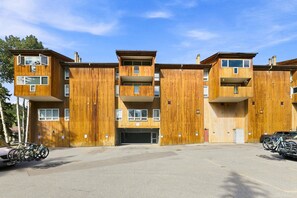 Ein mehrstöckiges Wohnhaus aus Holz mit Balkonen, einem Parkplatz und Fahrrädern.