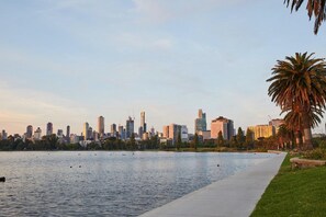 A city skyline with modern buildings, a body of water, and a palm tree. - Panoramic 2-Bed Apartment Near South Melbourne (South Melbourne)