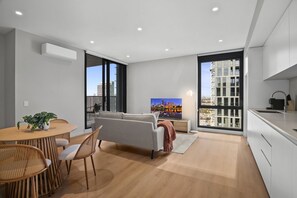 Un appartement moderne comprenant un coin repas, un canapé, une cuisine et de grandes fenêtres.
