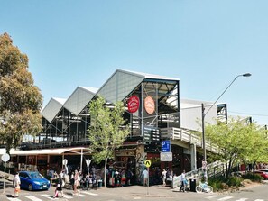 A modern building with a glass facade and a pedestrian walkway. - Panoramic 2-Bed Apartment Near South Melbourne (South Melbourne)