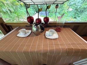 A table with a striped tablecloth, two white cups, a silver pitcher, and two red apples with leaves. - Costa Rican Country Style house in adorable Sámara Beach with cool AC breeze (Sámara)