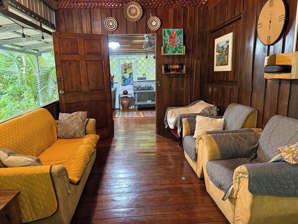A wooden-floored living area with a yellow sofa and a grey sofa, both with patterned cushions.