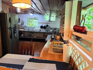 A kitchen with a refrigerator, stove, sink, and various kitchen utensils.