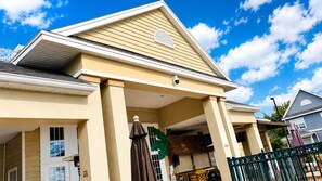 A two-story building with a flat roof, a covered porch, and a visible storefront with a sign. - Full BR Resort near Disney/Pool, Jacuzzi, Splash, Lake, Club House/& Family Fun (Kissimmee)