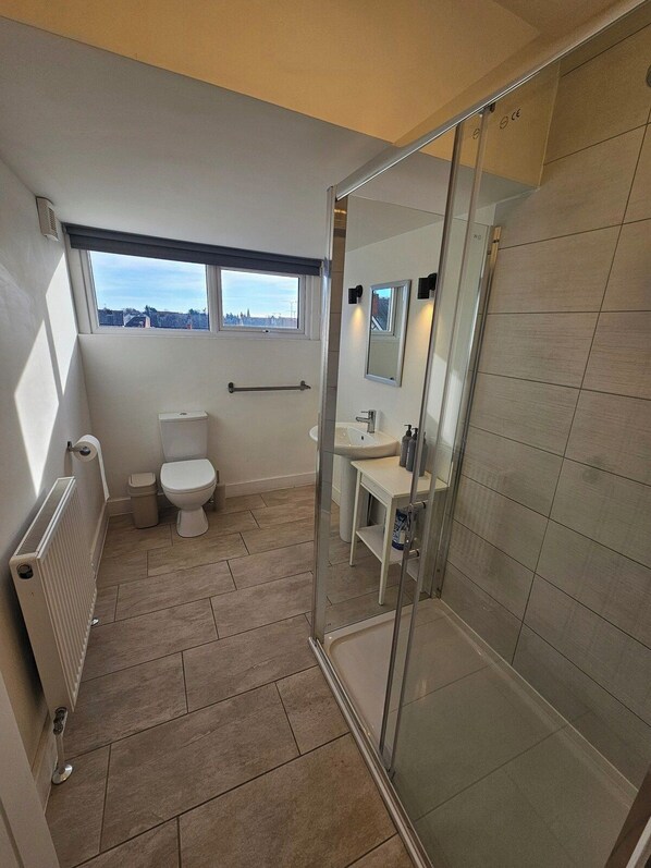 A modern bathroom with a toilet, sink, and shower area. - Market Quarter, town centre. free parking & wifi (Southport)