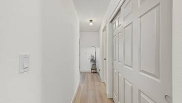 A hallway with white walls, wooden flooring, and a door with a traditional design.