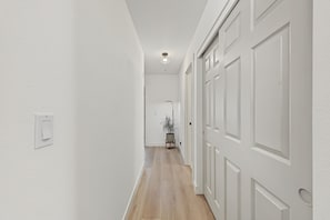 A hallway with white walls, wooden flooring, and a door with a traditional design. - Scottsdale Desert Retreat | Private Hot Tub (Scottsdale)