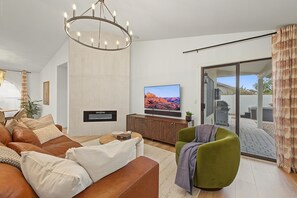 Een moderne woonkamer met een flatscreen televisie, een leren bank en een eethoek met een tafel en stoelen.