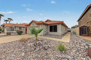 A residential area with houses featuring red-tiled roofs, a central palm tree, and a gravel driveway. - Scottsdale Desert Retreat | Private Hot Tub (Scottsdale)