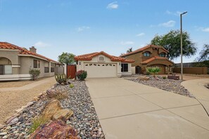 Un quartier résidentiel comprenant plusieurs maisons, une allée et un jardin aménagé avec des rochers et des cactus.