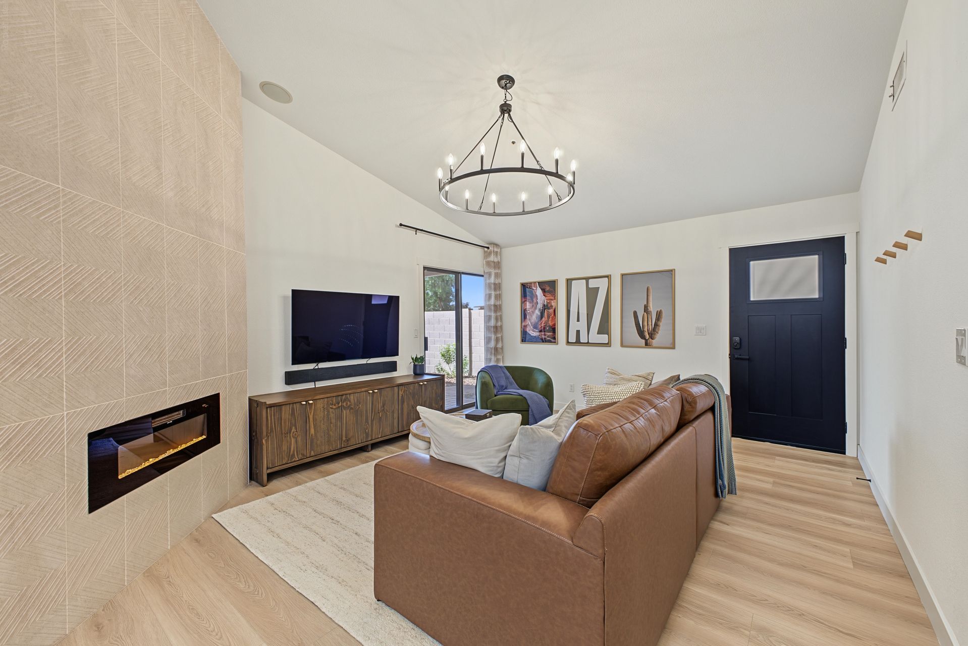 A modern living room with a flat-screen TV, leather sofa, and a chandelier.