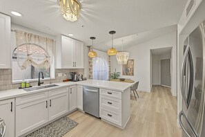 A modern kitchen with white cabinetry, a built-in dishwasher, and pendant lighting. - Scottsdale Retreat Private Hot Tub (Scottsdale)