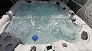 Uma banheira de hidromassagem com painel de controle, um objeto azul e uma janela.