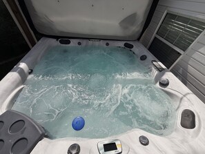 Una vasca idromassaggio con pannello di controllo, un oggetto blu e una finestra.