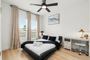 A bedroom with a bed, a desk, a chair, a ceiling fan, and a window with curtains. - Dallas–McKinney Luxury Retreat  5BR + Game Room (McKinney)