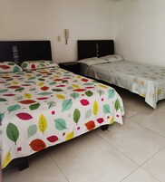 Habitación de hotel con dos camas, cada una con una colcha de estampado de hojas.