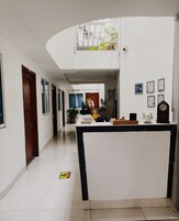 Un pasillo amplio con una mesa de recepción, un reloj y certificados enmarcados en la pared.