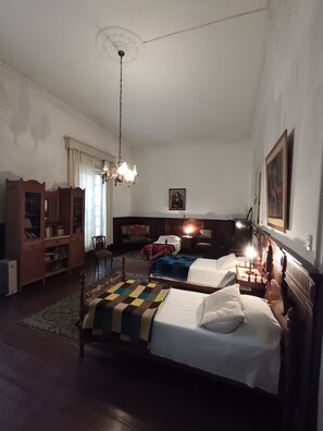 A bedroom with two beds, a wooden wardrobe, a chandelier, and a painting on the wall.