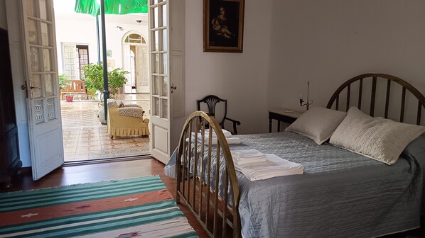 A bedroom with a bed, a chair, a bedside table, and a door leading to an outdoor area.